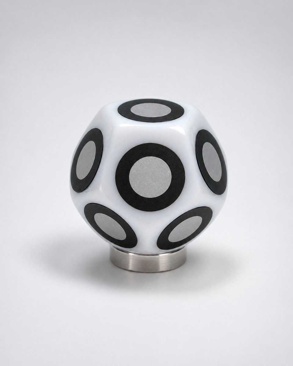 A PoseMark die on its magnetic standoff base — retroreflective targets on eleven faces